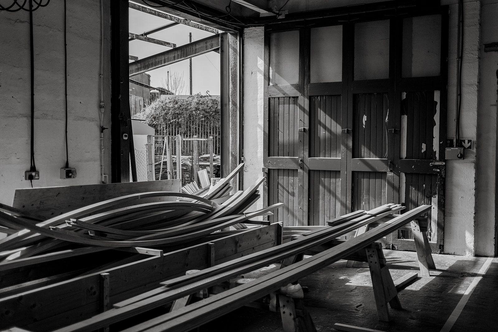 Straight and curved timber members for the lattice pavilion, with stacks of shaped timber behind.