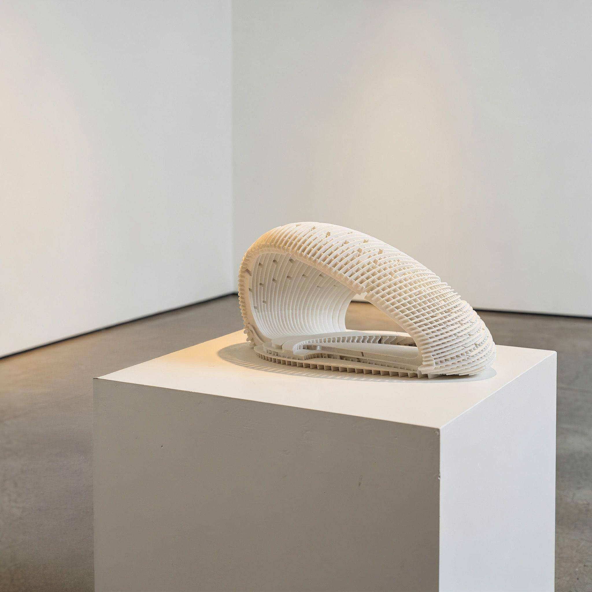White architectural model of the AA DRL Pavilion on a plinth, showing its curved lattice shell in miniature.