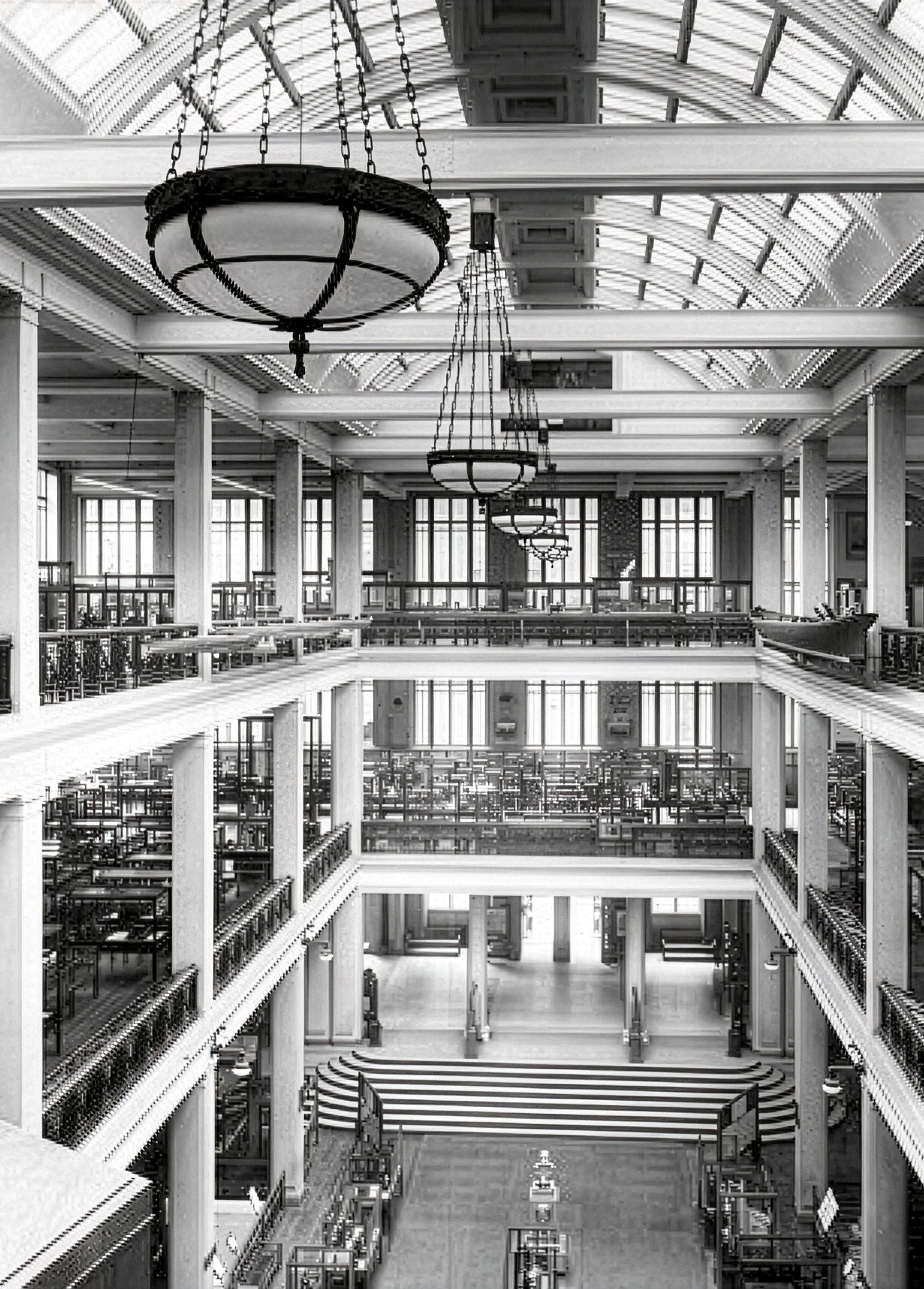 Archival photograph of the Science Museum's full-height central atrium, tiered galleries of exhibits rising beneath a glazed barrel-vaulted roof with suspended globe lights.