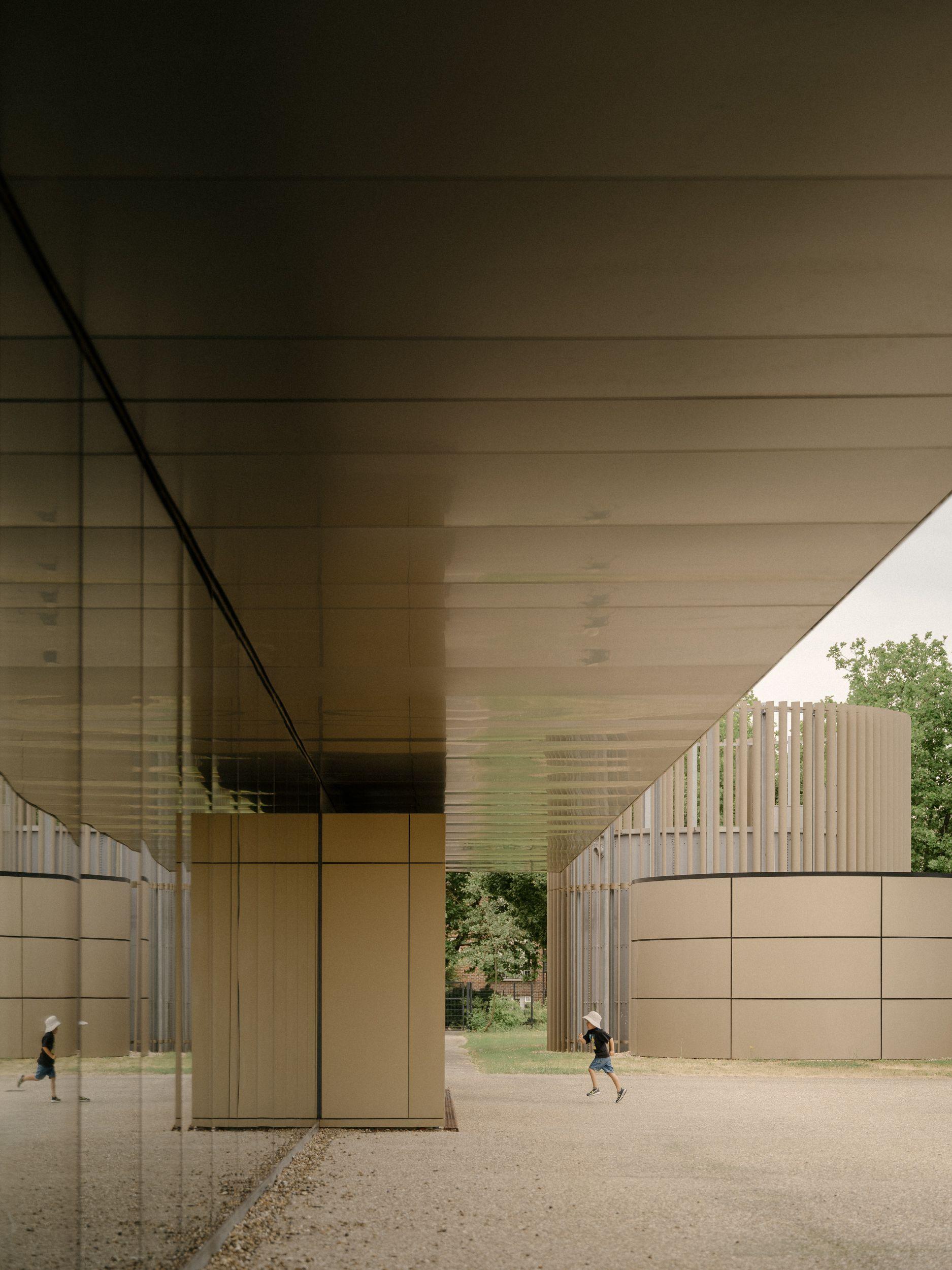 Beneath the cantilevered entrance canopy at the RAF Museum, London, a child running past the services pavilion beyond