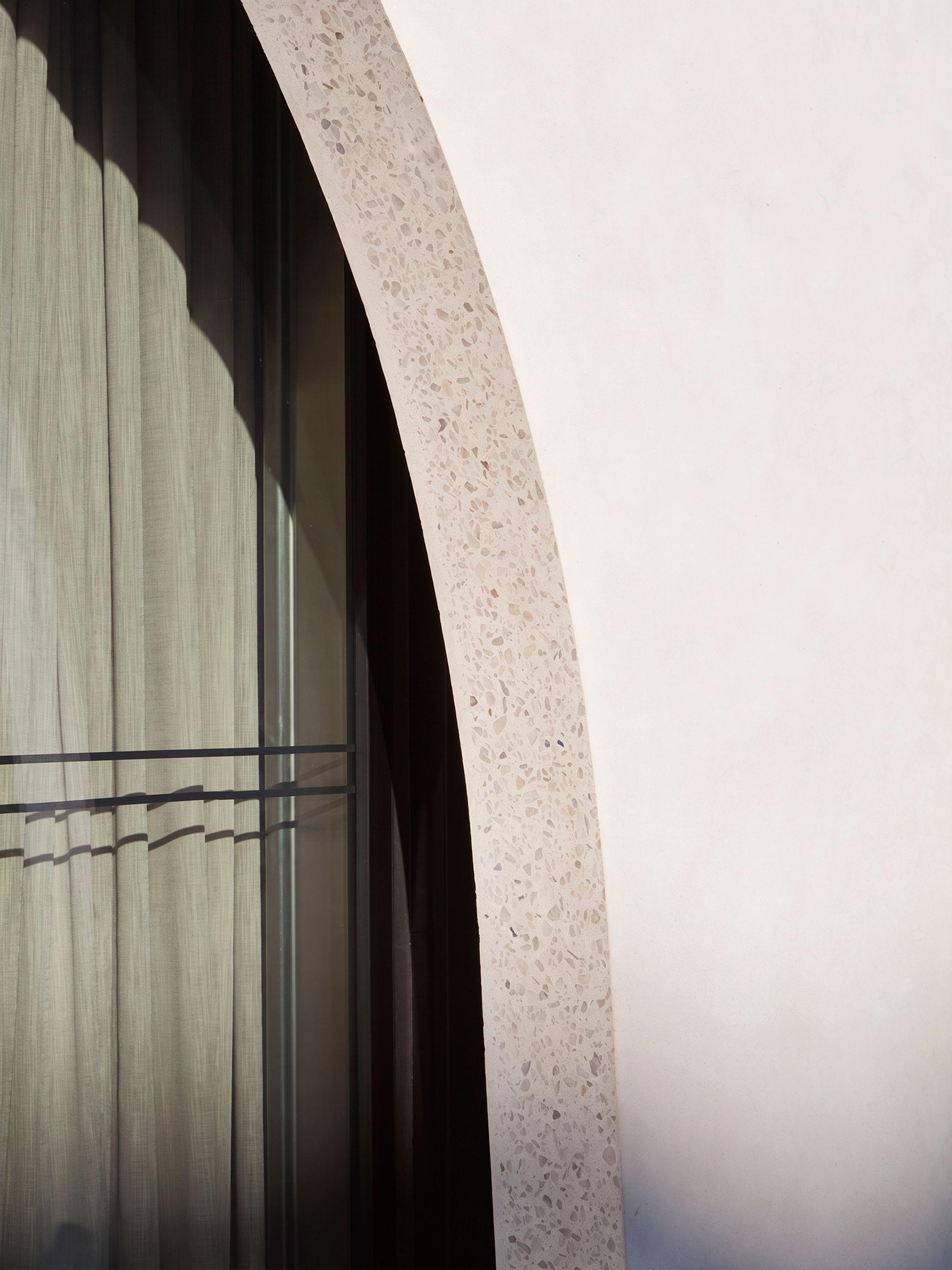 Alt text option 1 Detail of a polished terrazzo arch at Vardo, Duke of York Square, London, its natural stone patterning revealed against a plastered wall, with the retractable glazing and curtain behind.