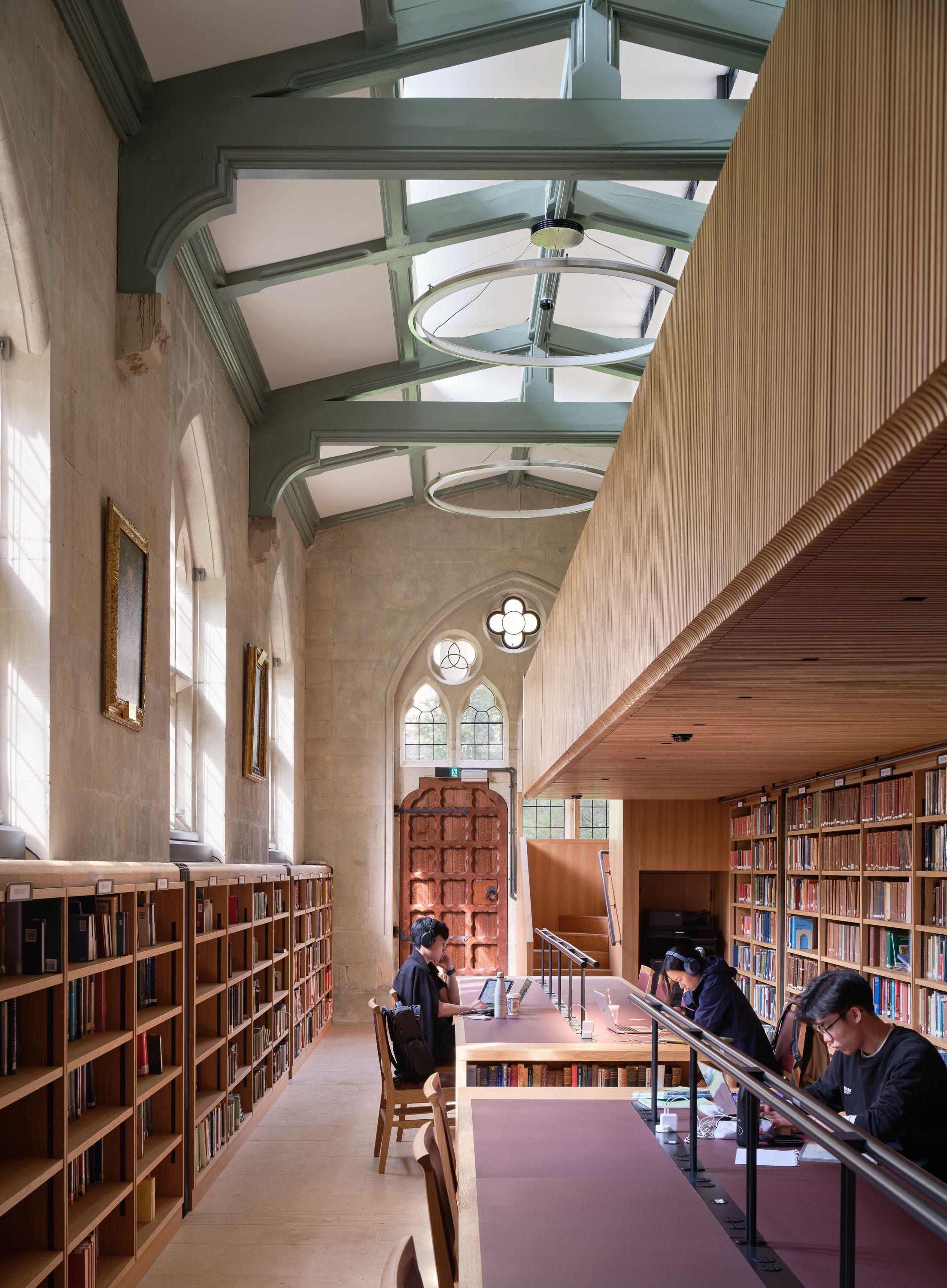 The annex at Exeter College Library, Oxford, with students at long study desks below the new timber balcony and clerestory windows in the replacement roof above