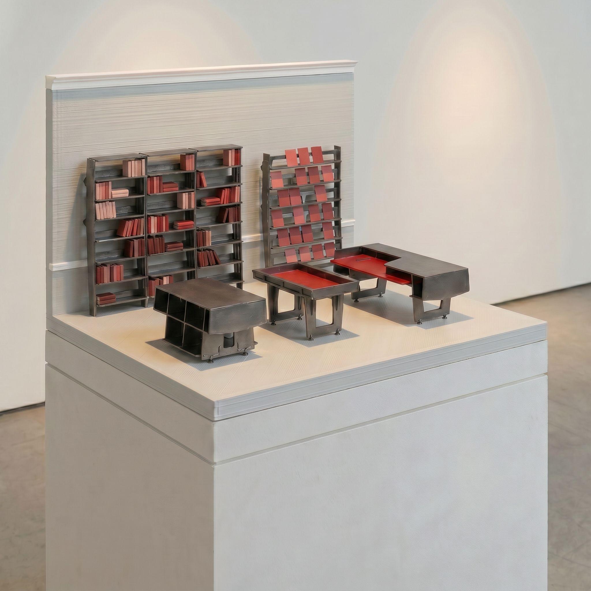Scale model of the AA Bookshop fit-out, its shelves and glass-topped tables rendered in dark metal with red books and magazines.