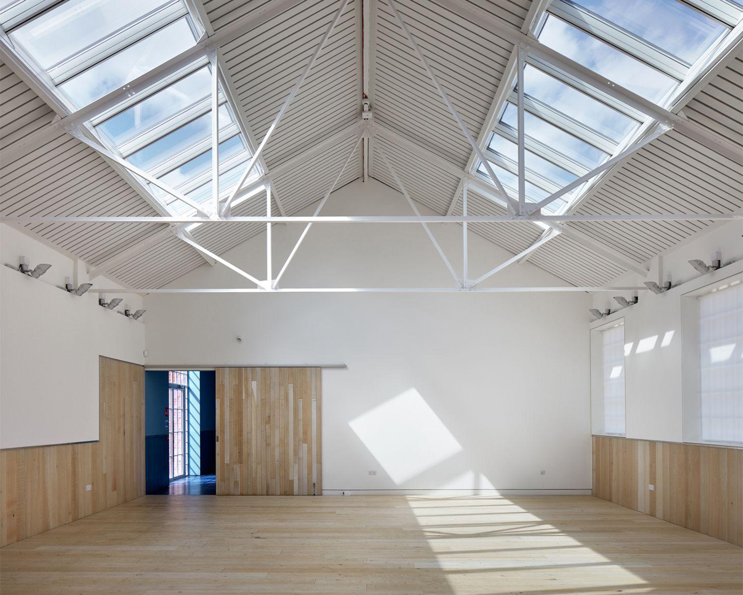 A top-lit events room in the restored supplies building at the RAF Museum, London, its timber partition drawn open