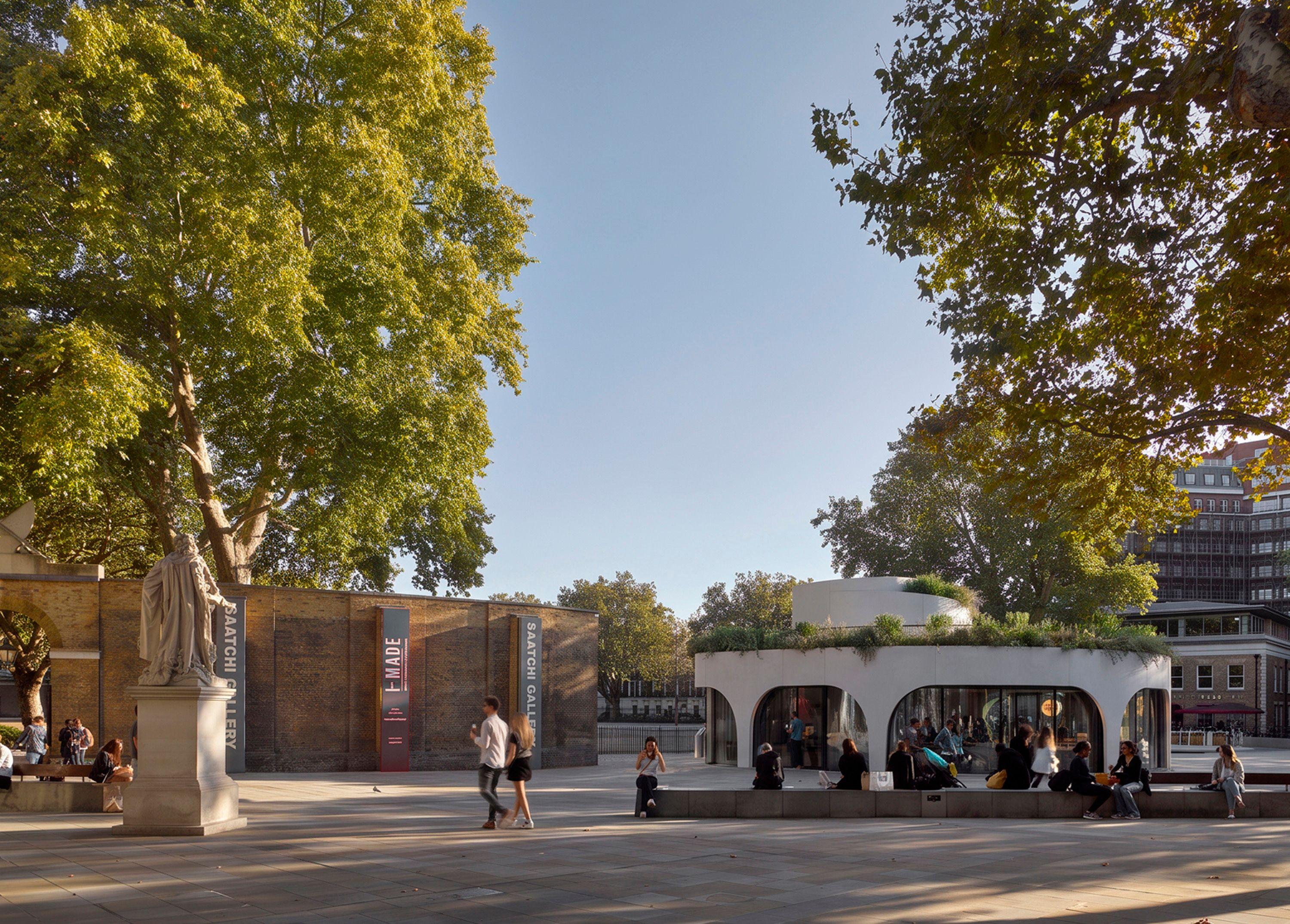 Vardo in its wider setting at Duke of York Square, Chelsea, London, its curved planted form beside the historic asylum wall and the Saatchi Gallery, with people crossing the square.